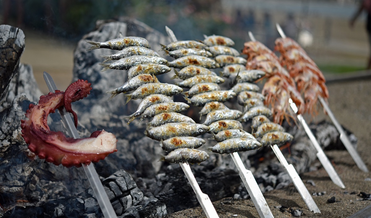 Sardines grilling over a charcoal fire on the beach