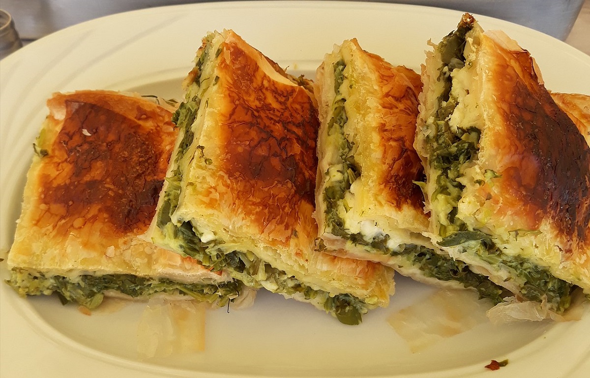 4 squares of Greek spinach pie overlap on a white plate