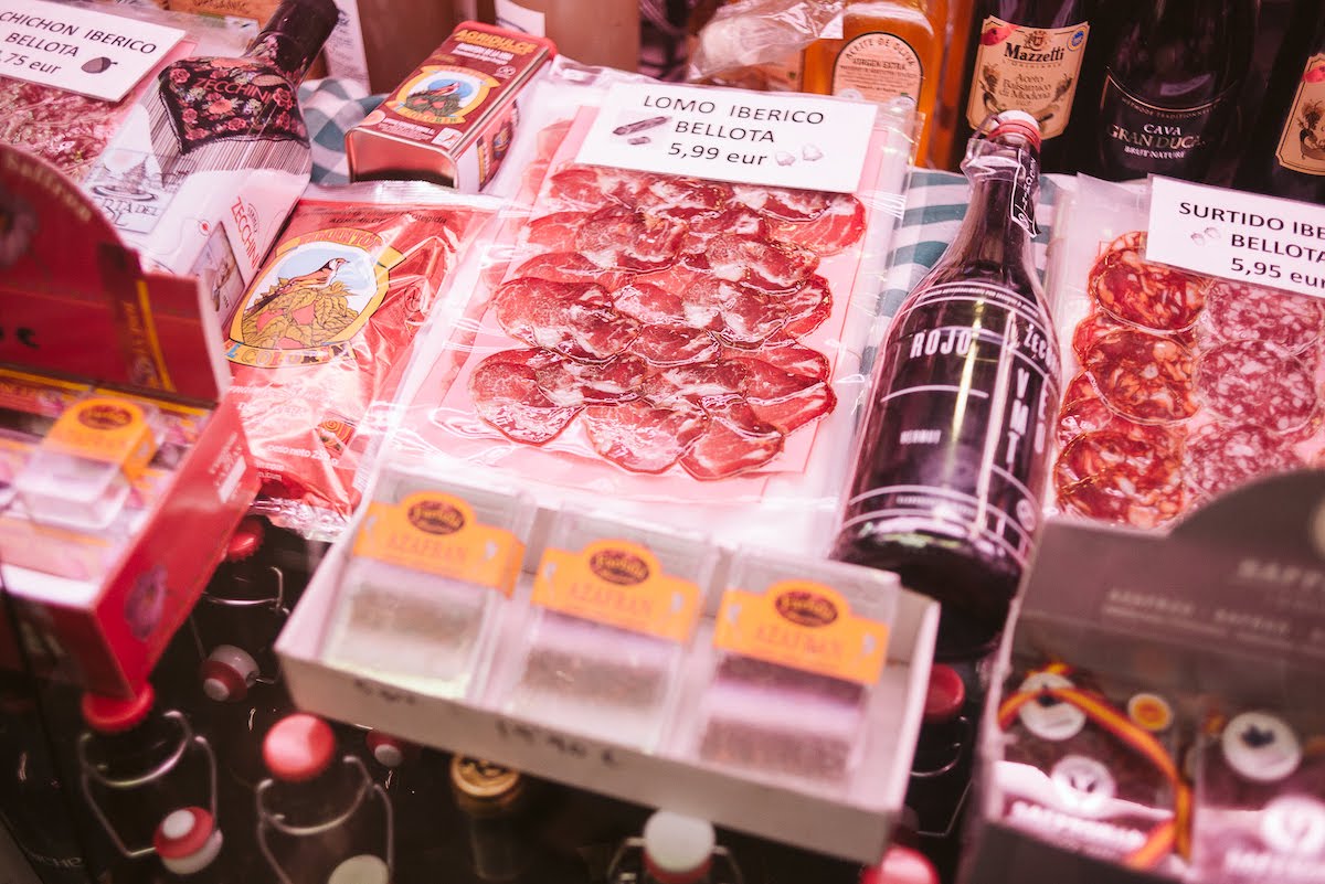 Selection of cured meats, spices, and other gourmet products at a traditional Spanish market stall.