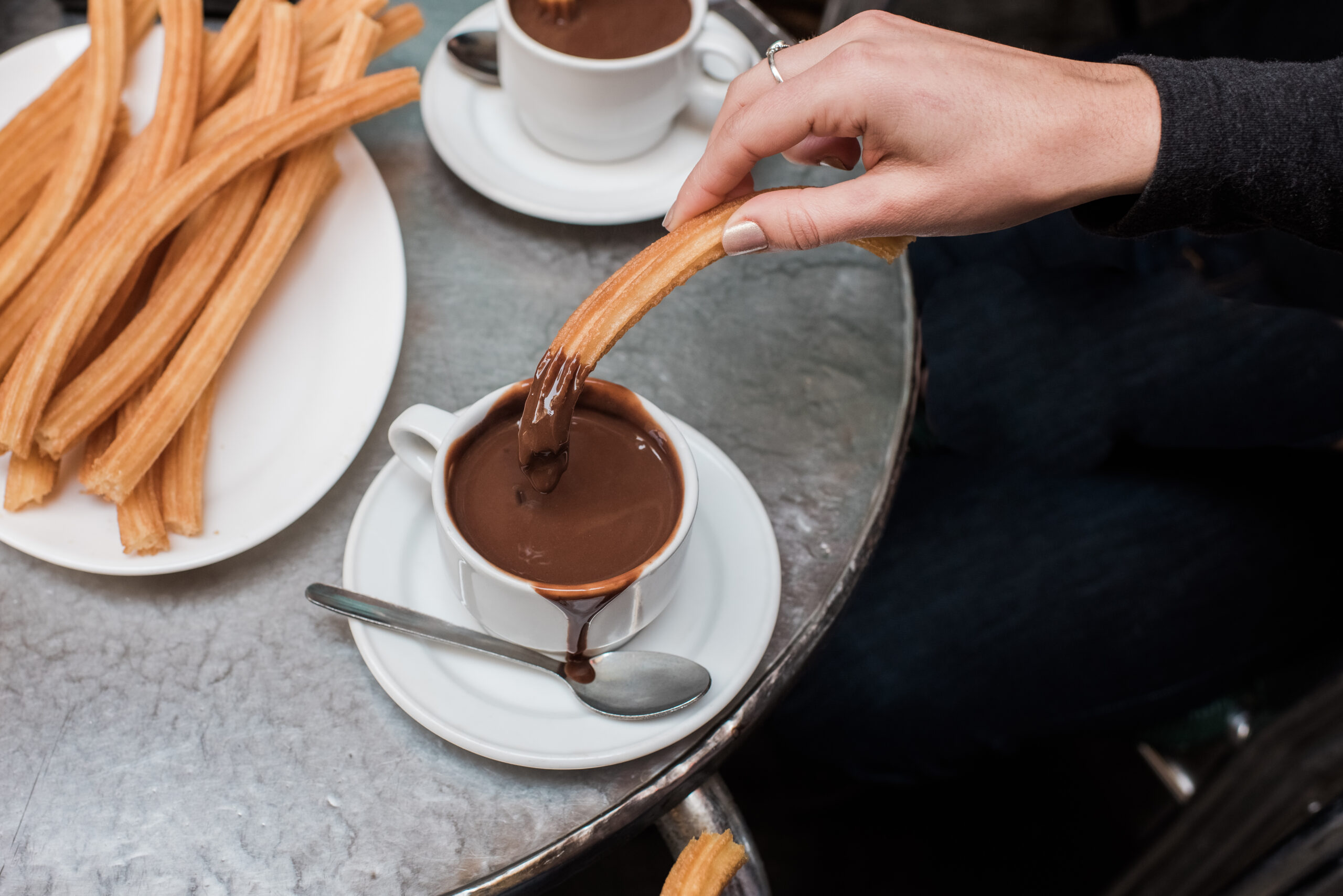 Churros dipped in a cup of chocolate 