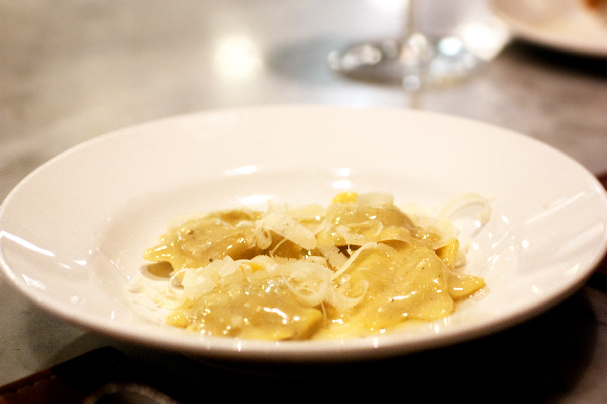Ravioli in a light sauce served on a white plate.