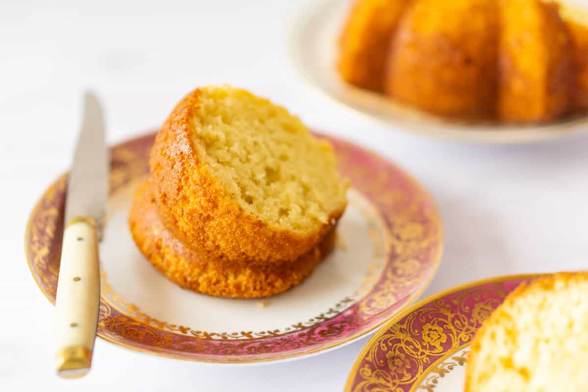 A slice of lemon sponge cake on a white plate with a knife