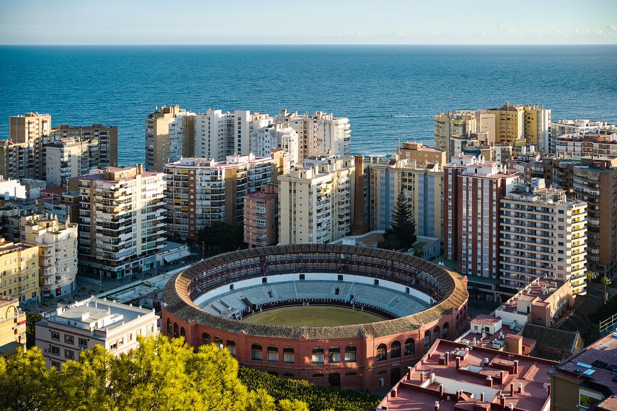 Aerial view a bullring surrounded by skyscrapers and calm blue sea in the background