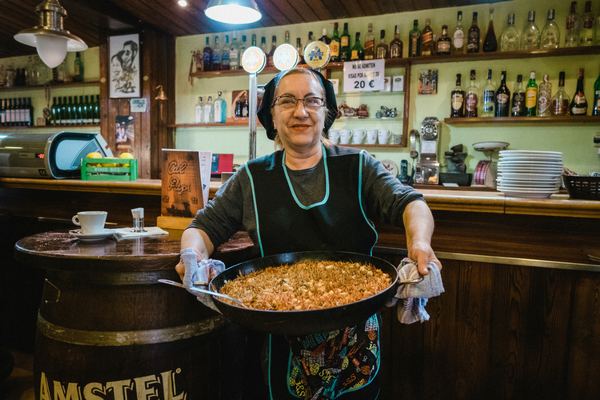 Chef Carmen holding a pan of her famous fideuà