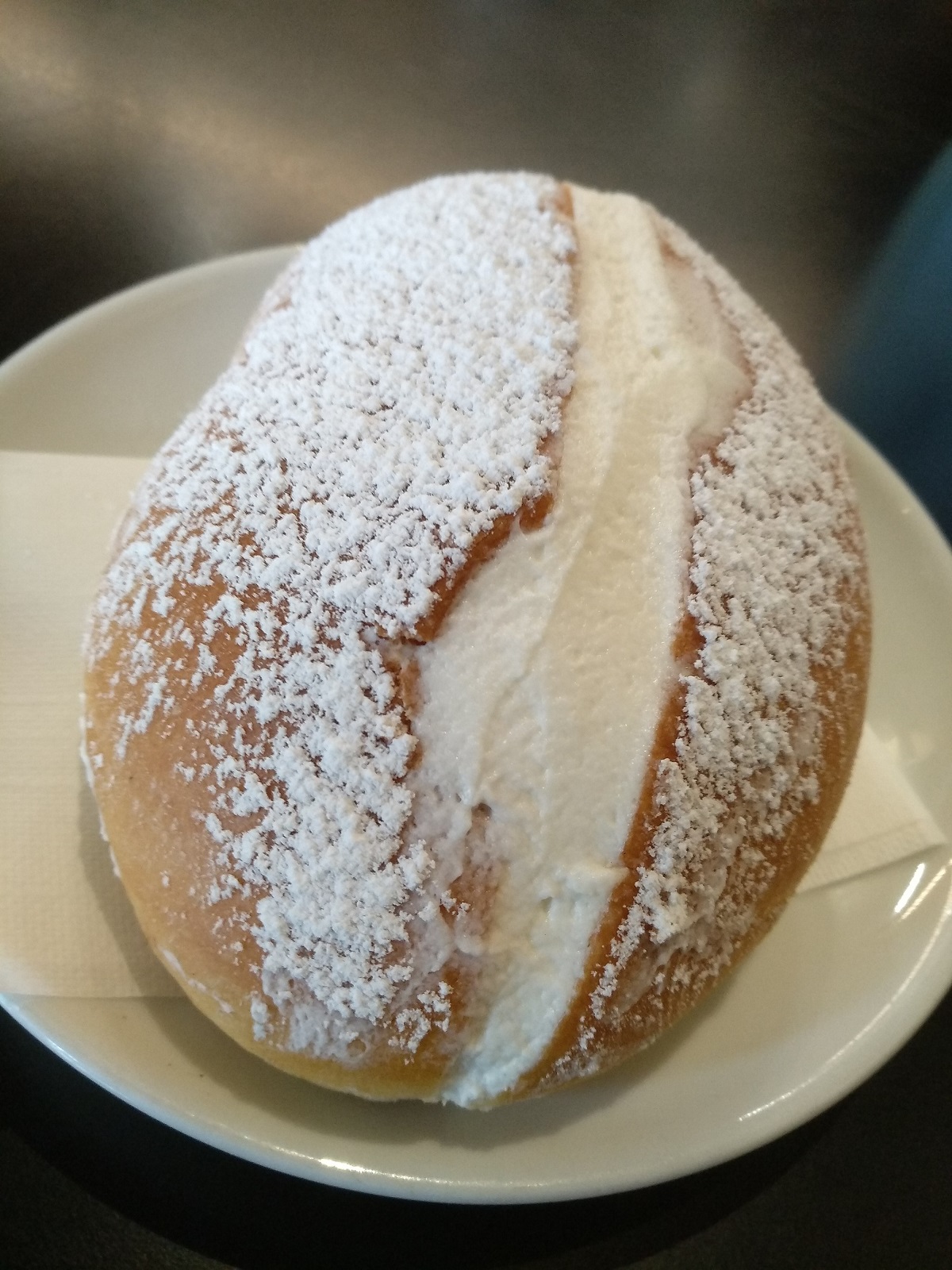 Close up of maritozzo with powdered sugar on a white plate