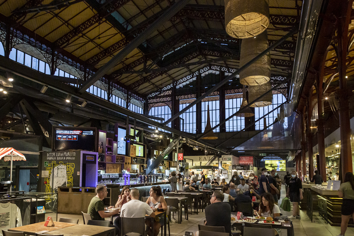 Interior of a large indoor food market with several restaurant stalls