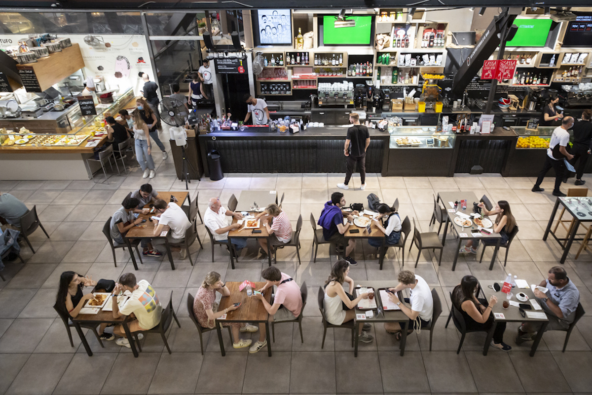 Overhead shot of people eating at tables inside a food market