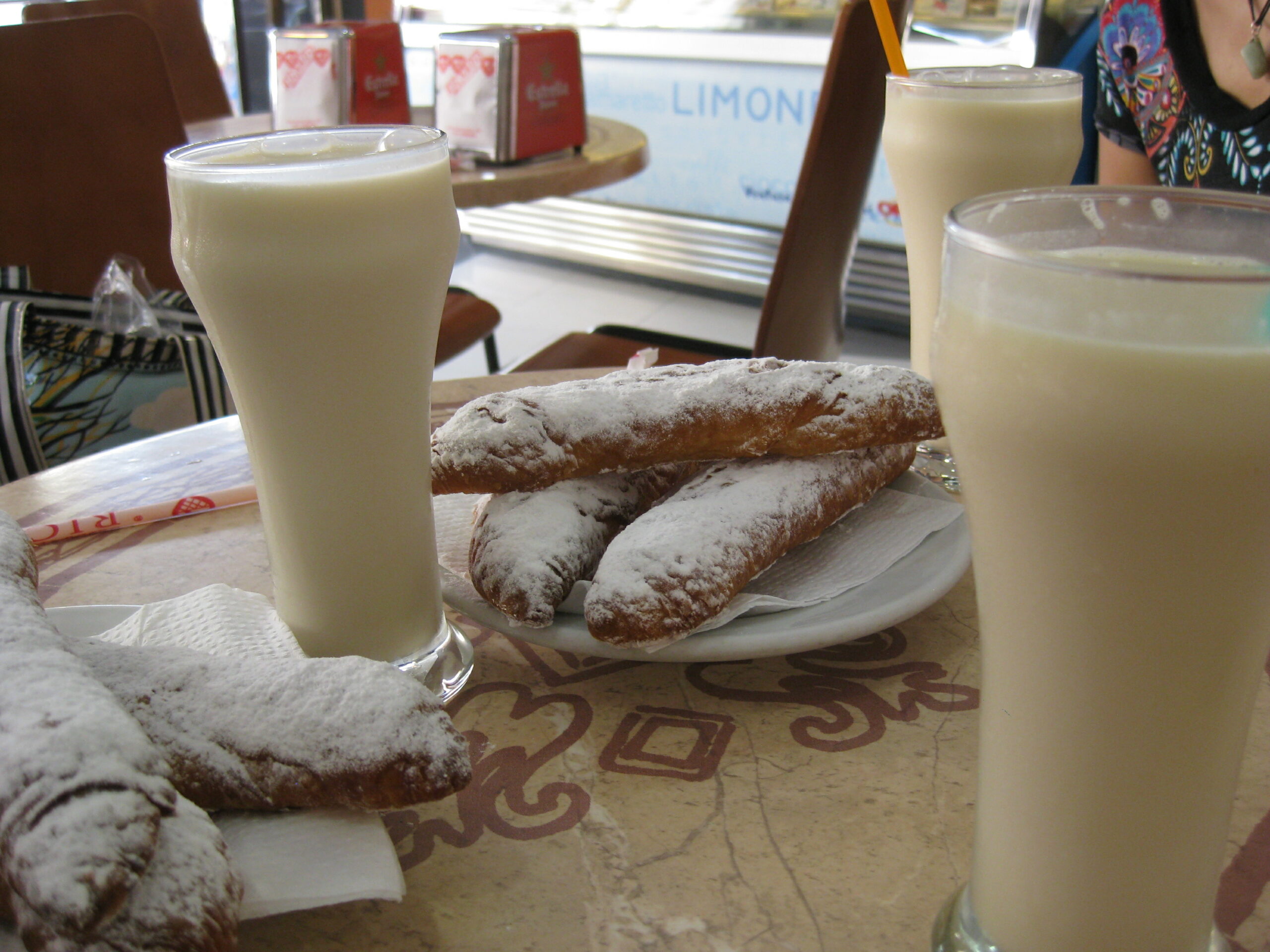 Glasses of horchata with a plate of fartons with sugar on top