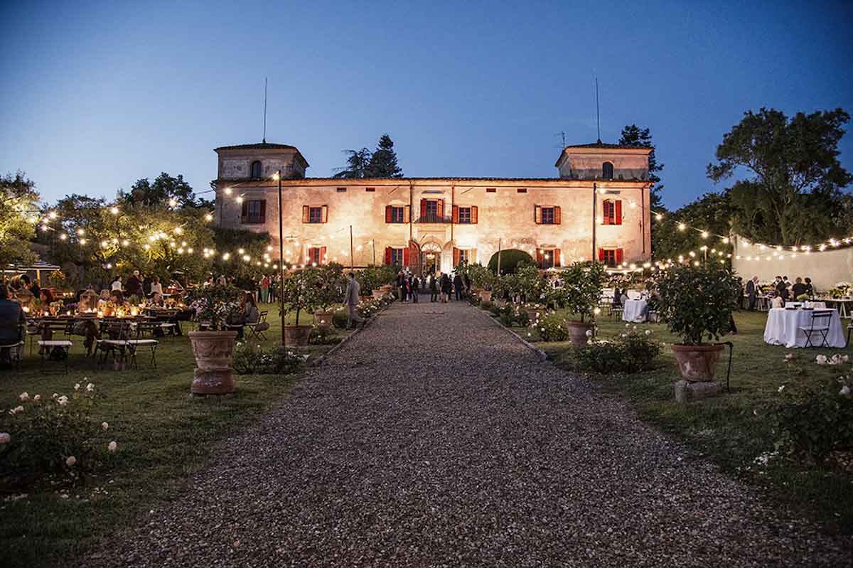 Stately Italian villa lit up by exterior lighting at dusk 