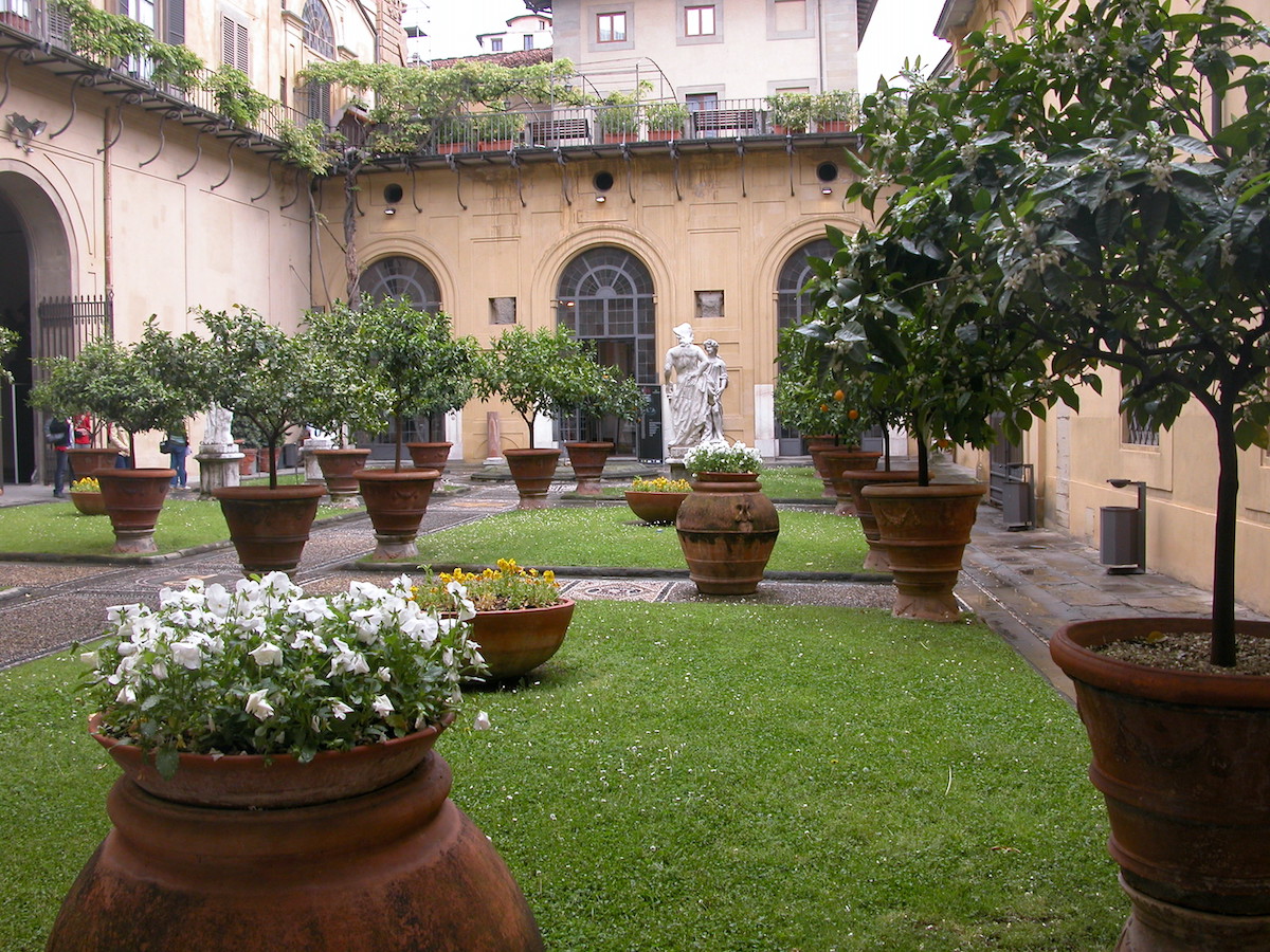 Inner courtyard of Renaissance palace with stone walking paths and large potted plants