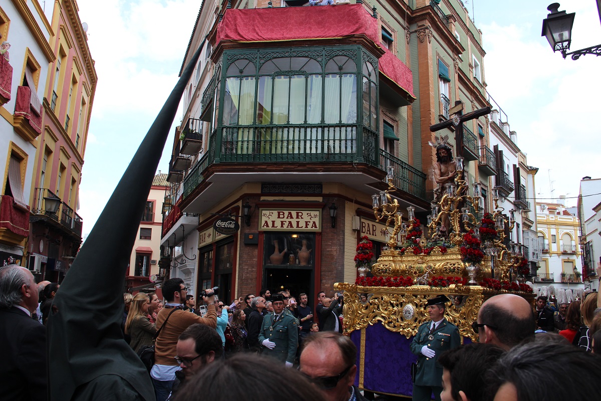 A golden float with a religious statue parading through the street in Seville