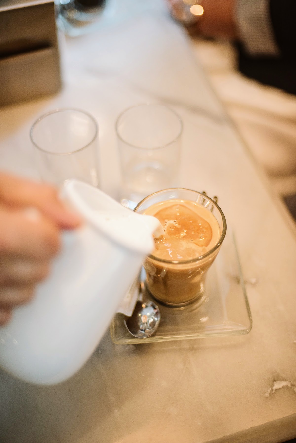Pouring milk into glass of coffee