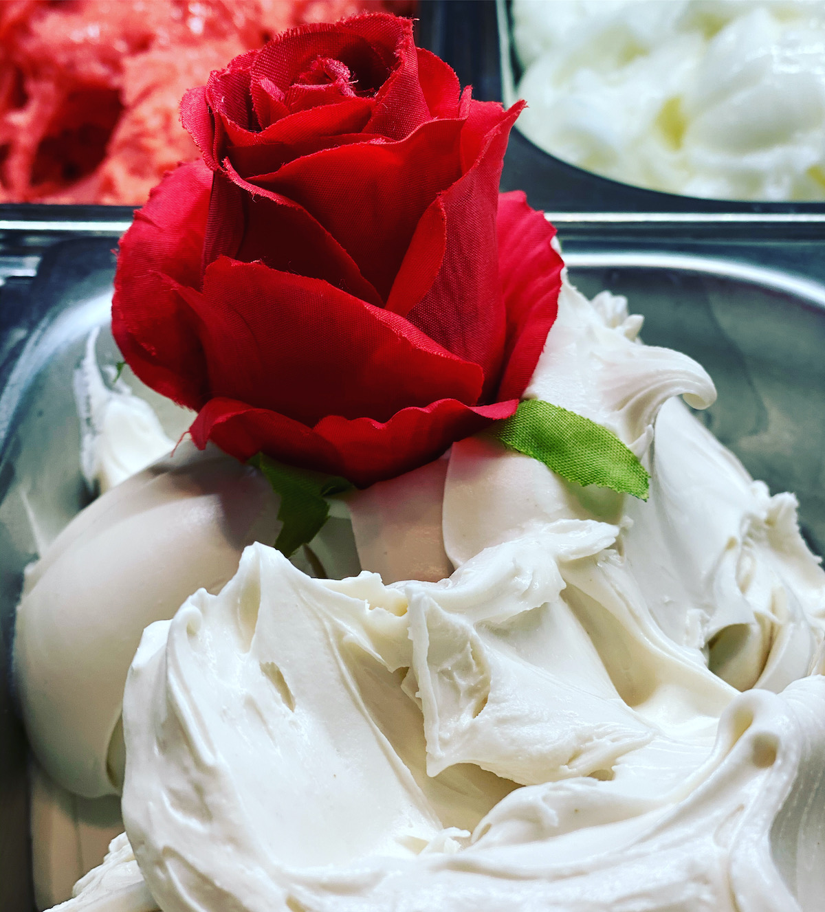 White gelato displayed at a shop decorated with a red rose