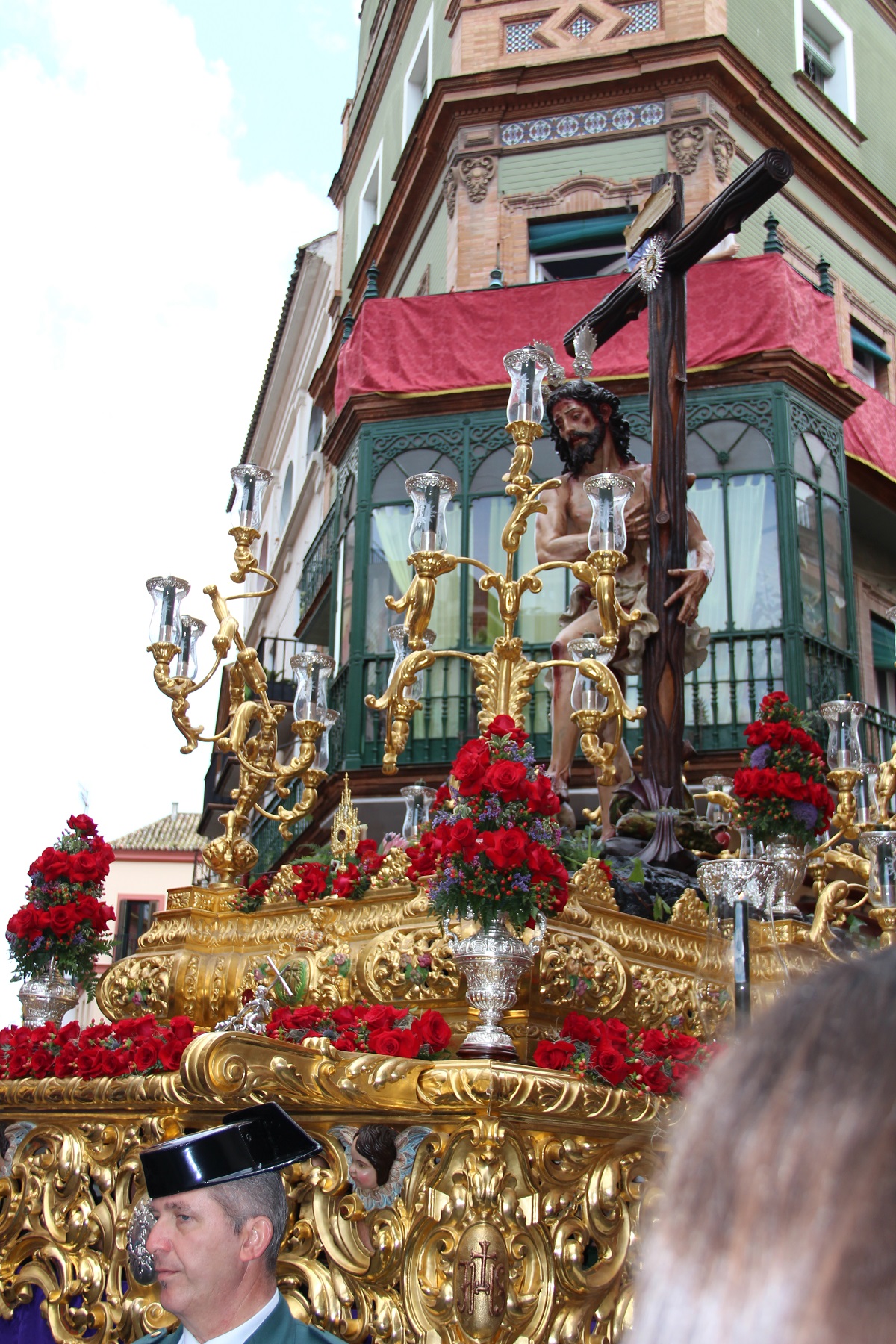 A a gold float with a religious statue of Jesus standing next to the cross carried through the streets of Seville
