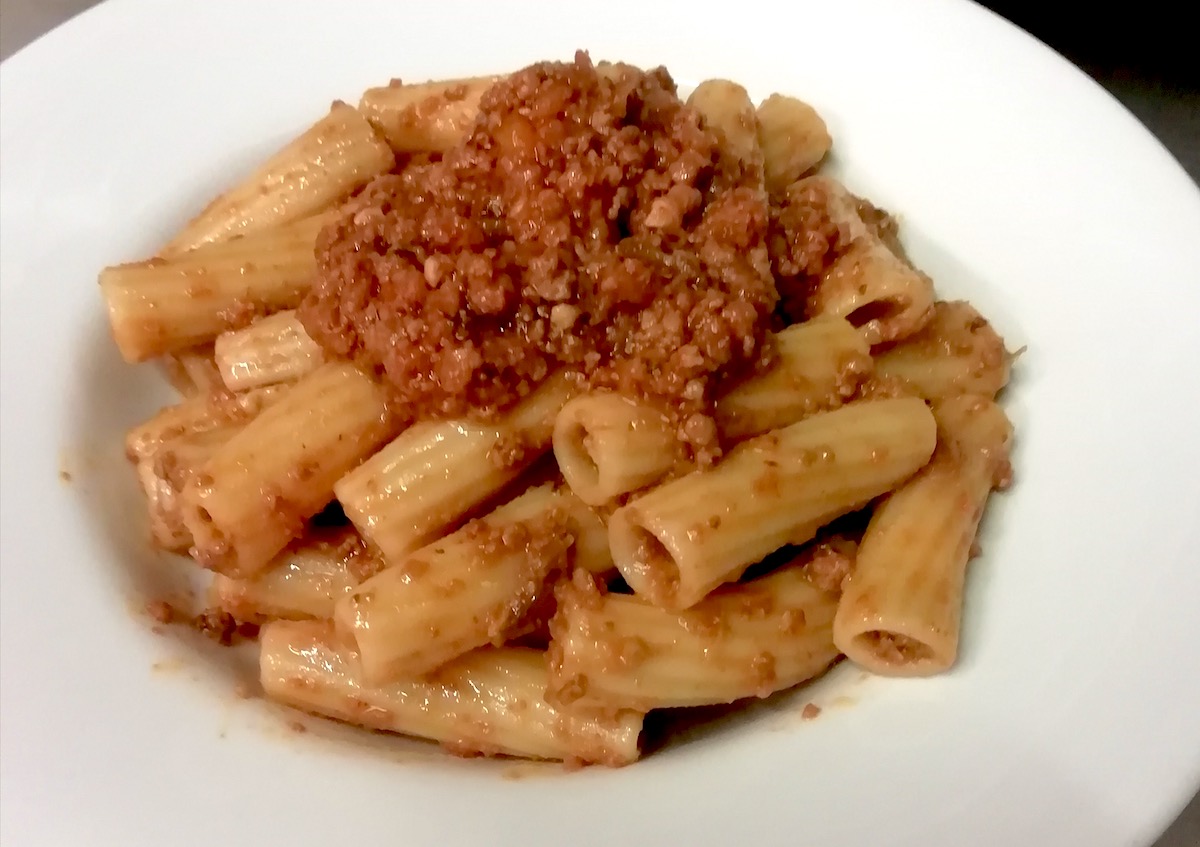 Rigatoni pasta with meat sauce on a white plate.