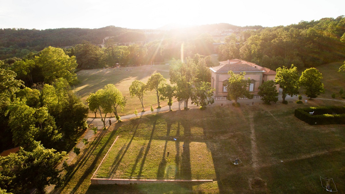 Sun coming down on a villa in Tuscany with many trees and long shadows