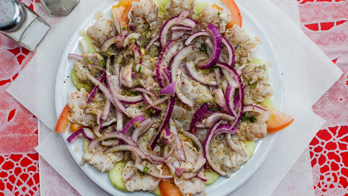 A plat of aguachiles, with seafood, red onions, cucumber, and spices