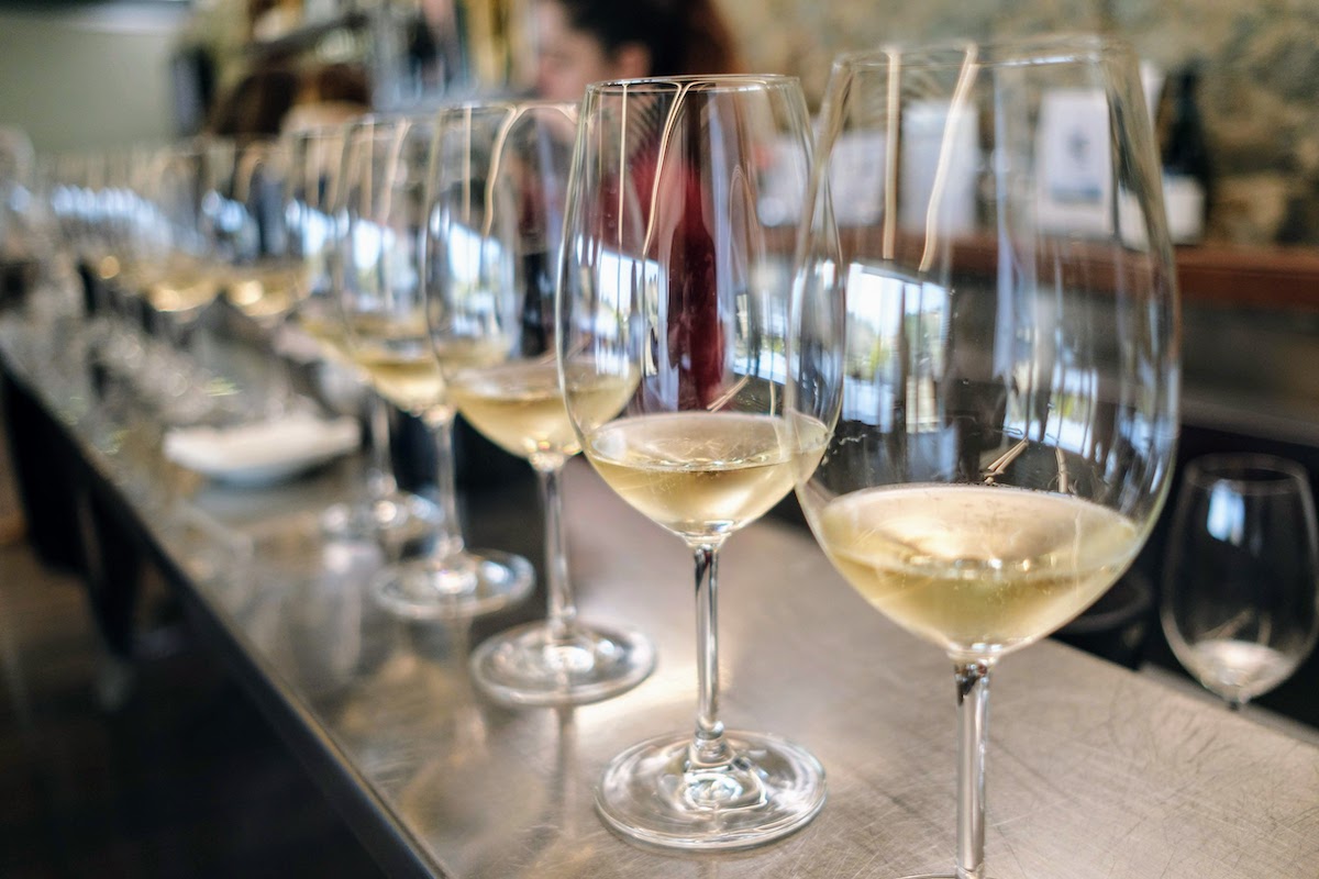 Glasses of white wine lined up on a bar.