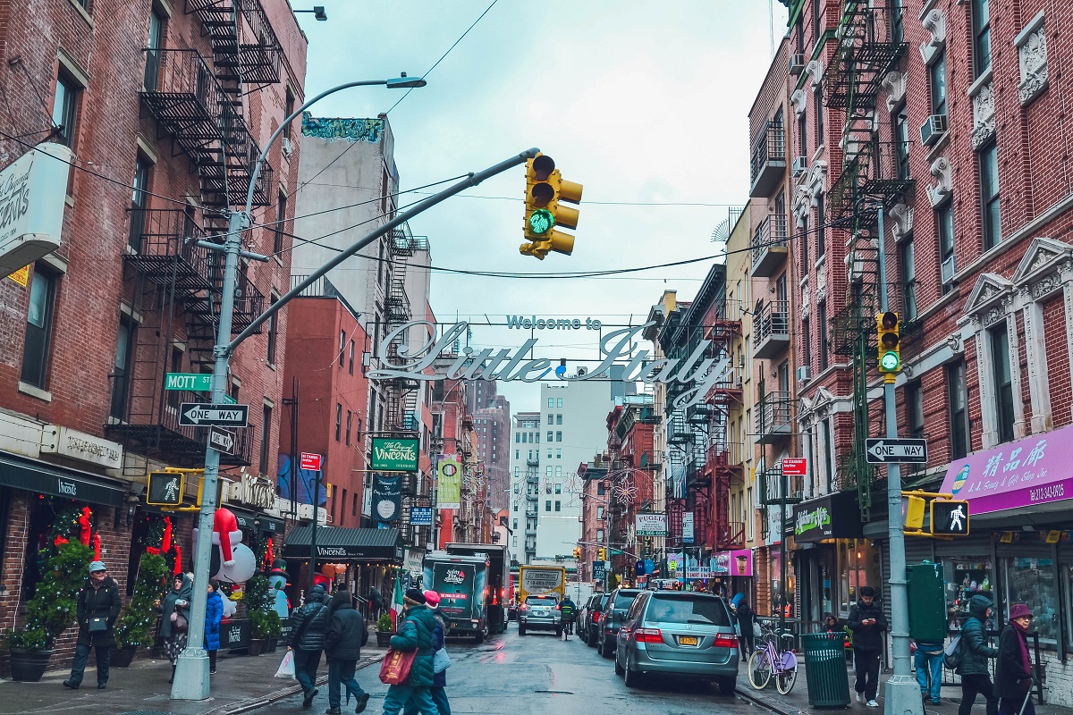 Busy street scene in NYC's Little Italy, with stop lights, cars, and pedestrians