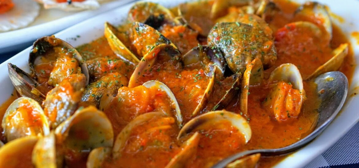 Clams in a red sauce on a white plate