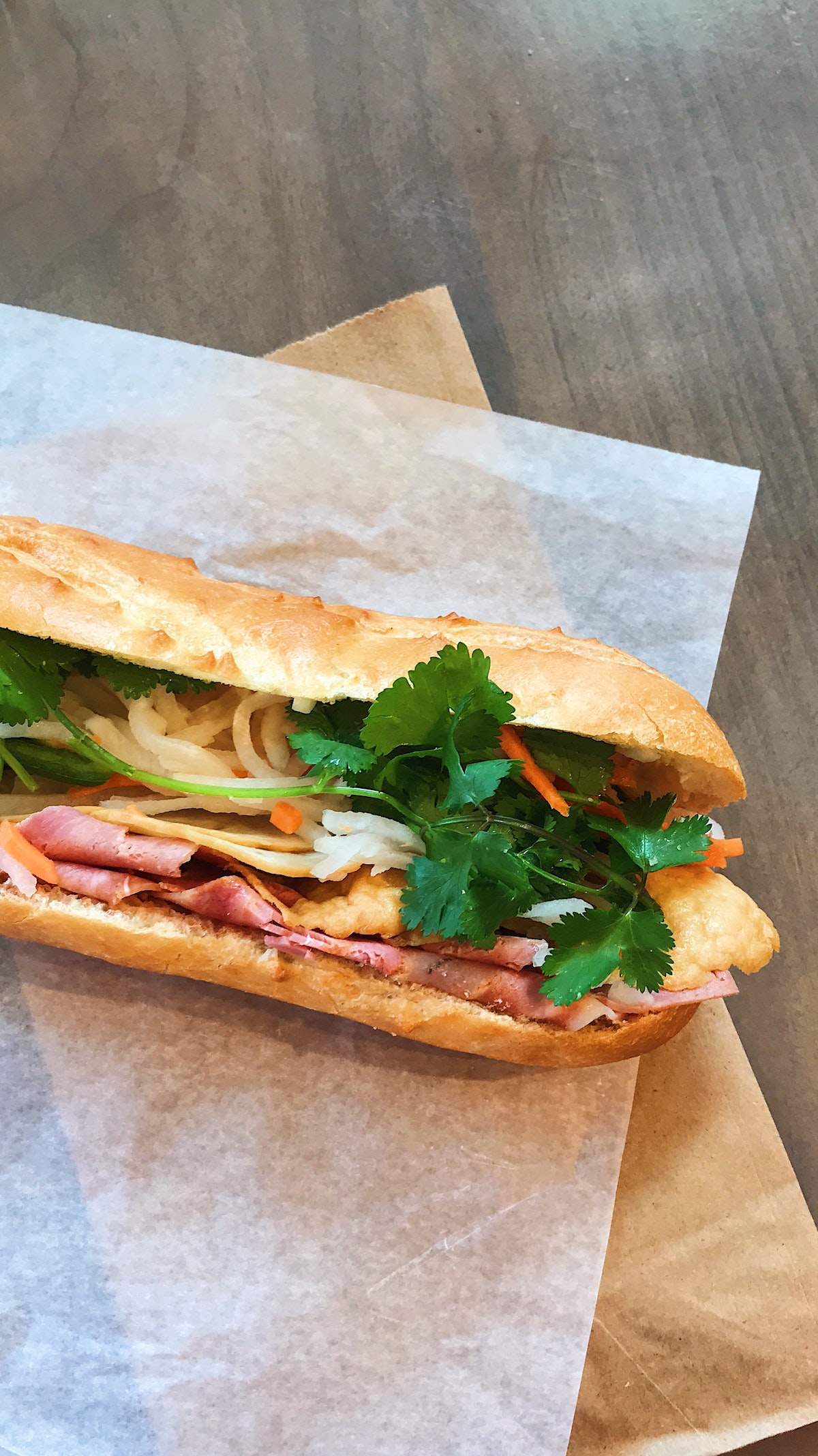 Close up of a banh mi sandwich, a baguette cut lengthwise and filled with meat and vegetables