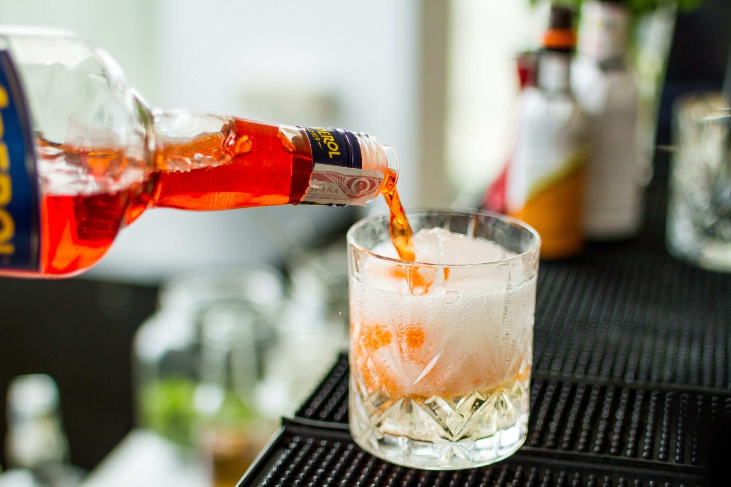A bartender pouring aperol spritz into a glass