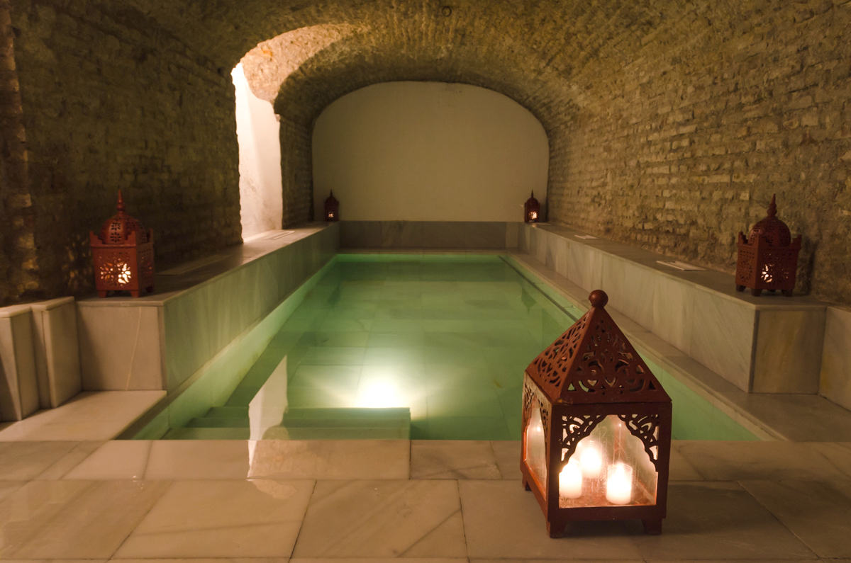 Interior of Arab-style bath house with brick walls and a rectangular pool. A great place to go in Madrid when it rains.