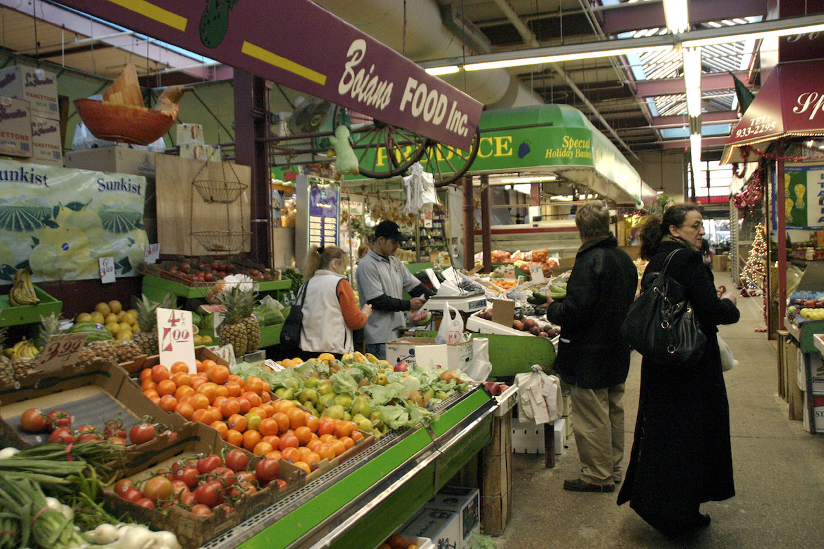 People standing near a fresh produce stall in a market