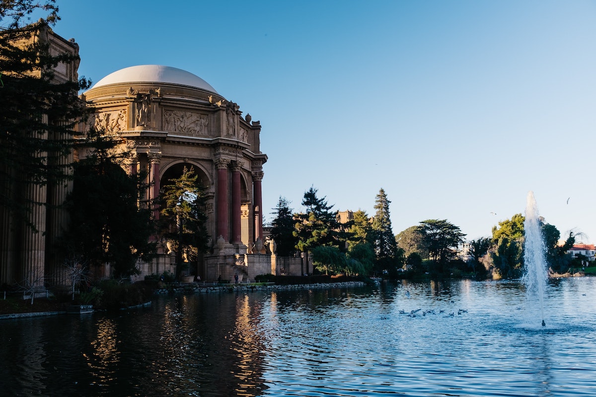 A photo a pond with the dome of the Palace of Fine Arts peeking up in the background. Visiting the Palace of Fine Arts is a fun free thing to do in San Francisco