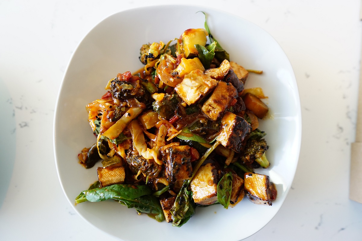 A bowl of stir-fried vegetables and tofu in a white dish