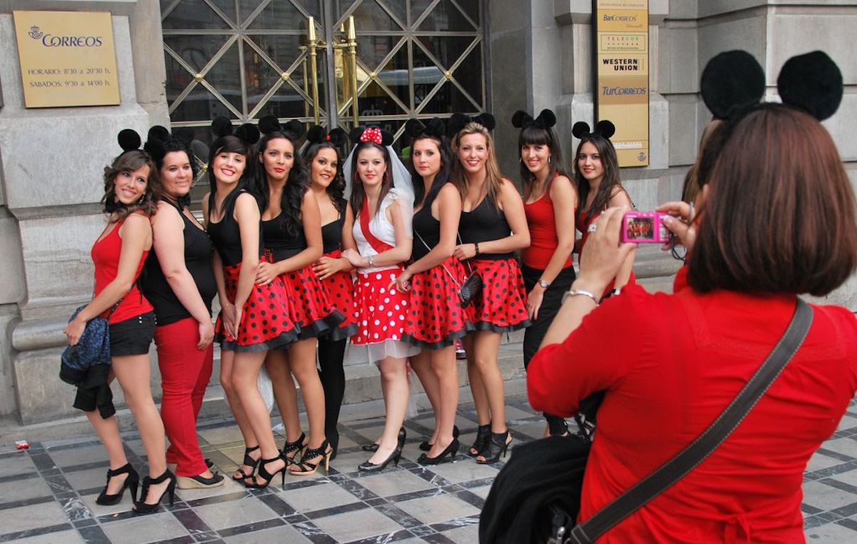 Bachelorette party group in black and red outfits and Mickey Mouse ear headpieces posing for a photo.