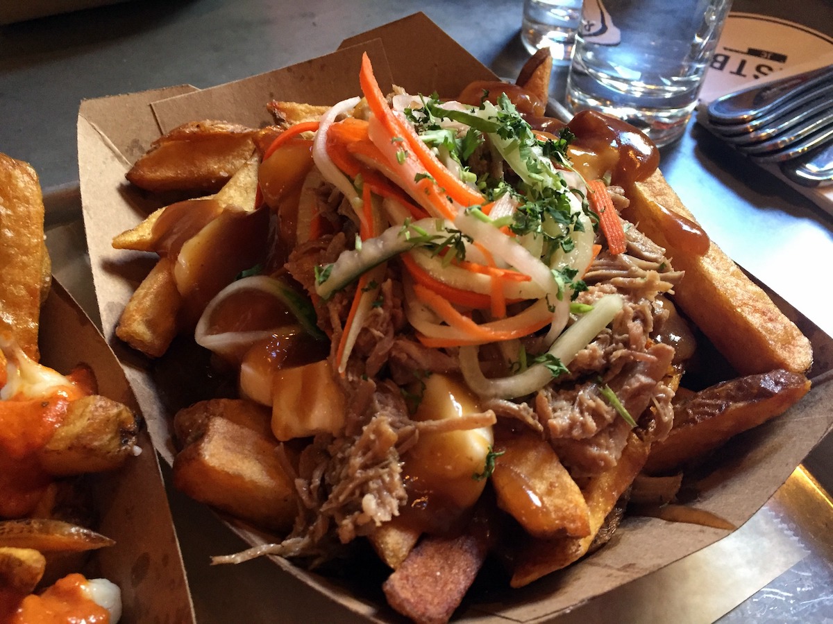 Hand cut fries topped with cheese curds, shredded pork, slaw, and other ingredients.