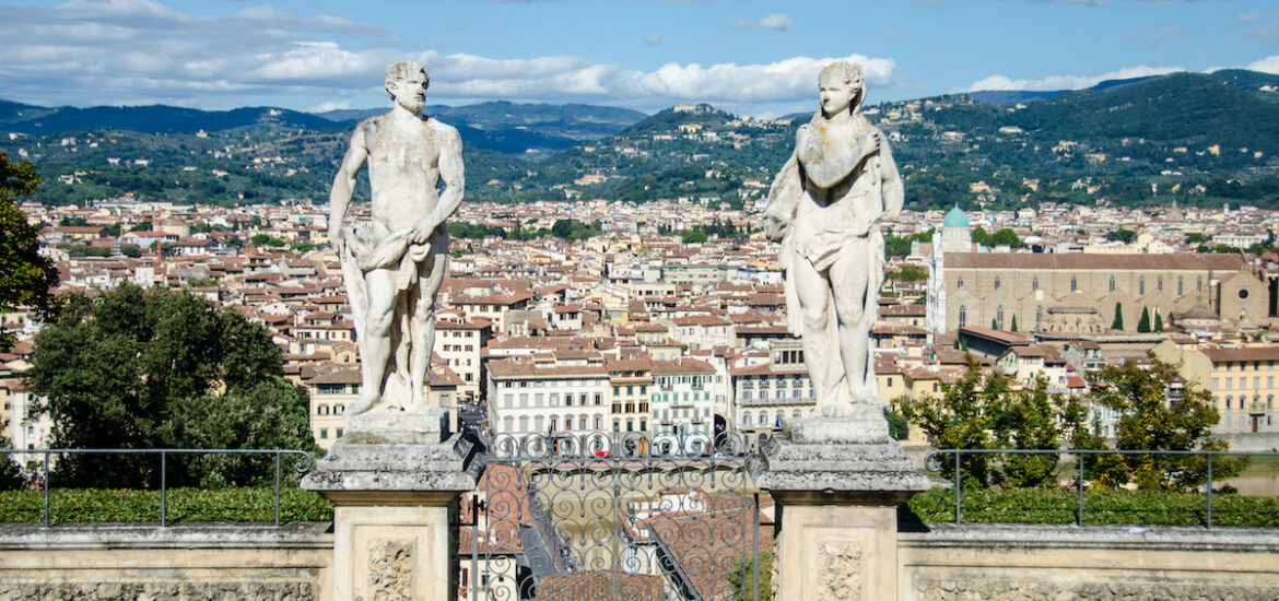 Two stone statues framing a panoramic view over the city of Florence, Italy