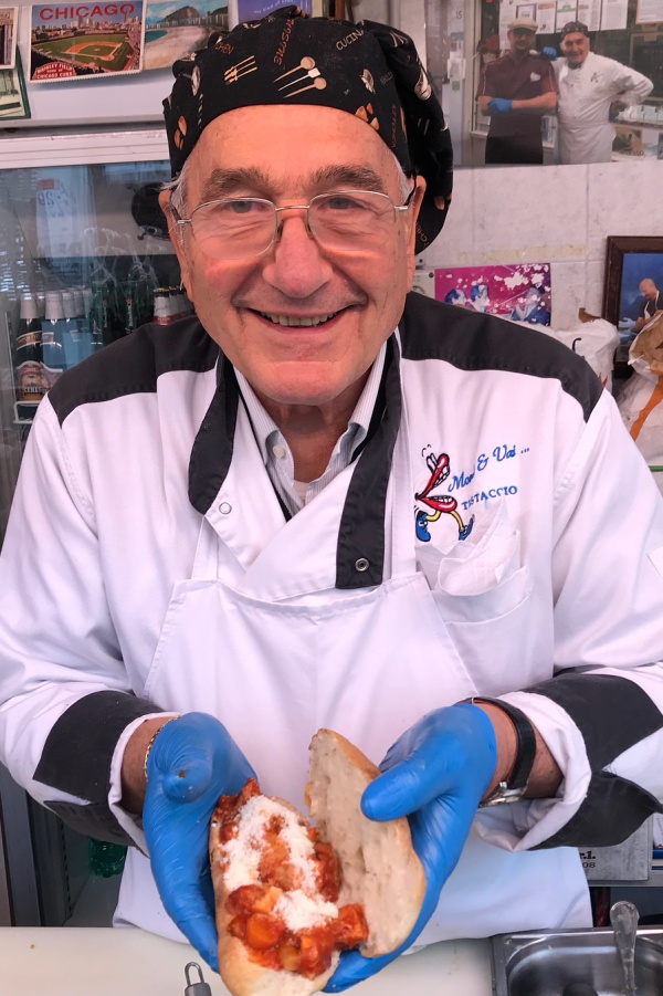 Sergio of Mordi e Vai showing off a trippa alla romana sandwich for lunch in Rome.
