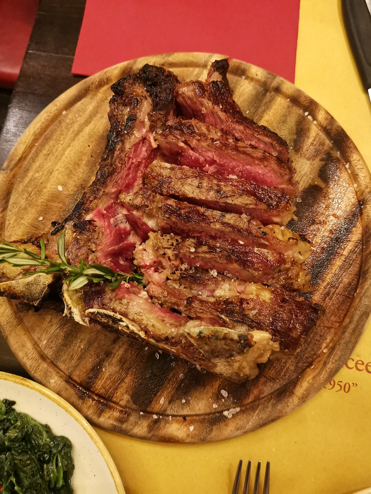 Overhead shot of sliced rare steak on a wooden plate garnished with herbs