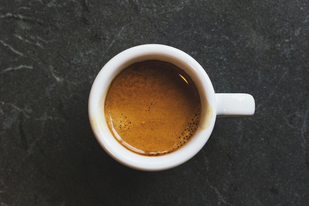 Overhead shot of espresso in a small white cup against a dark background