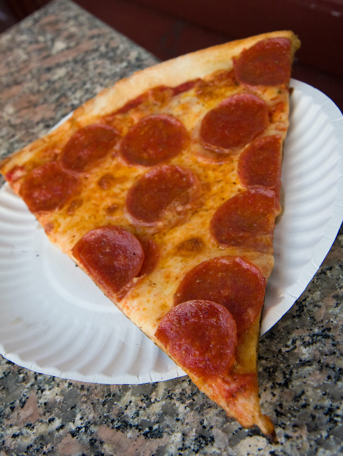 Slice of pepperoni pizza on a paper plate