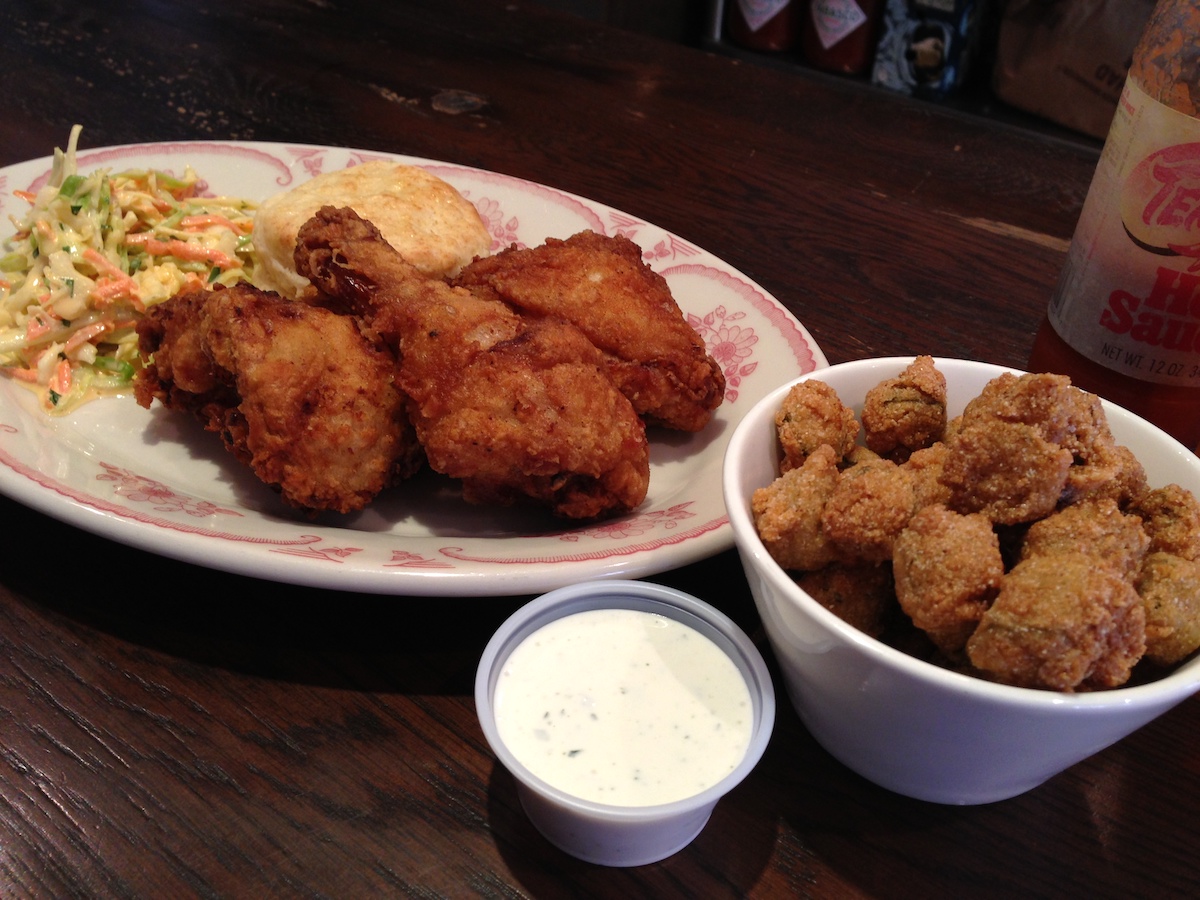 Plate of fried chicken next to a bowl of fried okra and a small container of white dipping sauce