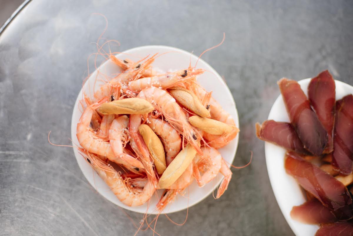 Overhead shot of whole cooked shrimp and small breadstick crackers on a white plate