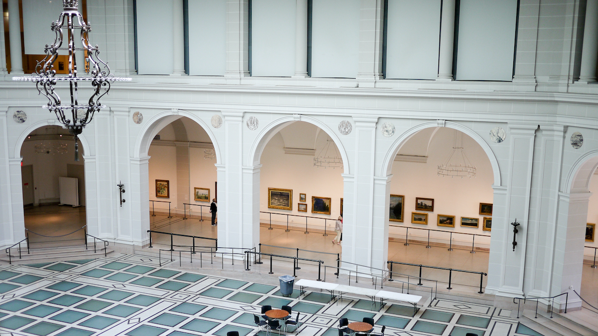 Interior of an art museum with teal-tiled floors, light fixtures, and archways