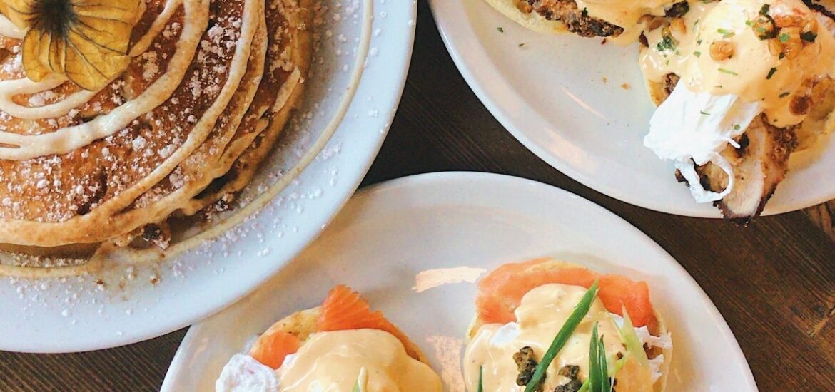 Overhead shot of eggs Benedict, pancakes, and other brunch items