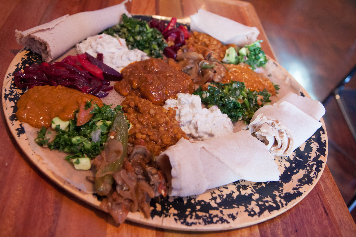 Platter of vegan Ethiopian food with rolled up flatbreads, vegetables, and beans