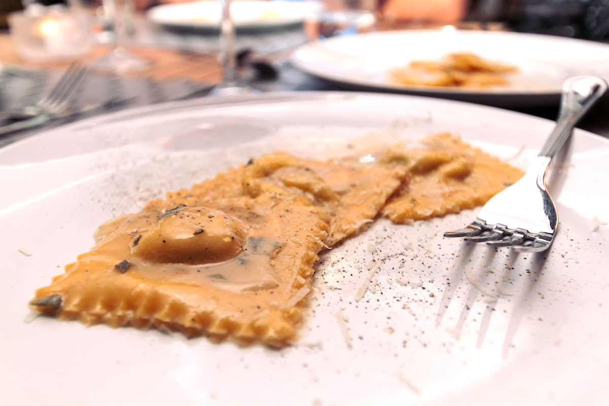 Three ravioli beside a fork on a white plate
