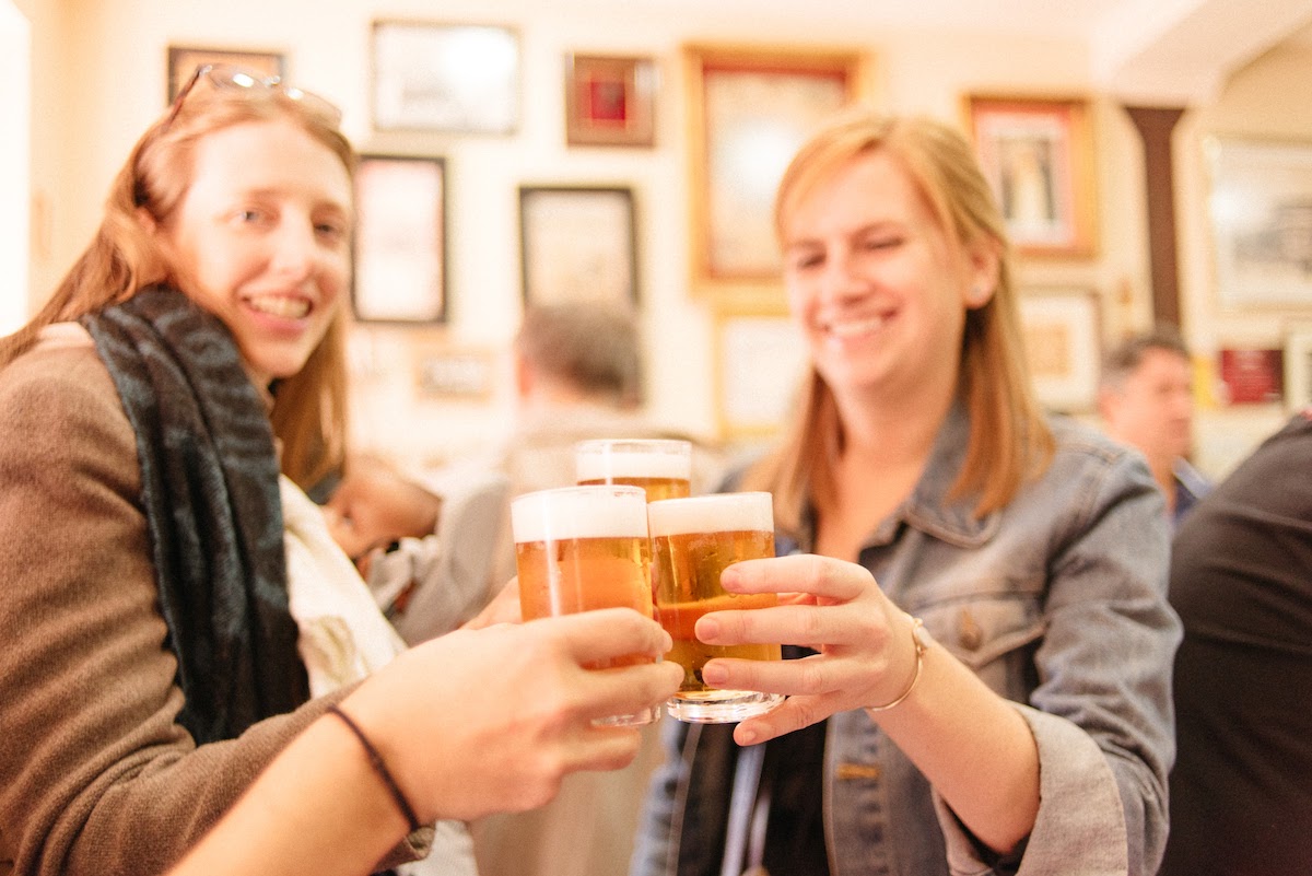 A group of women toasting with small glasses of beer