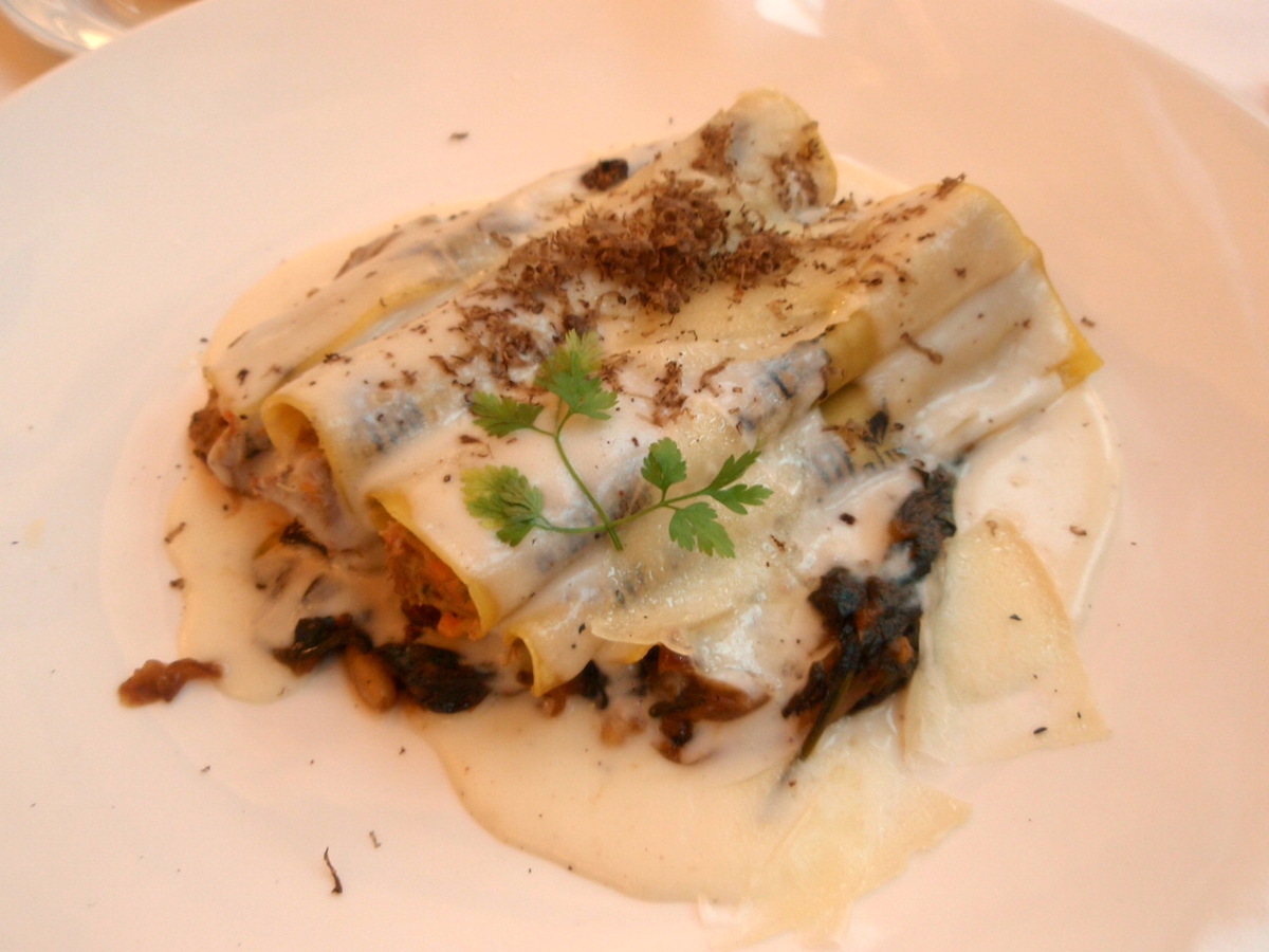 Cannelloni covered with white sauce and garnished with herbs