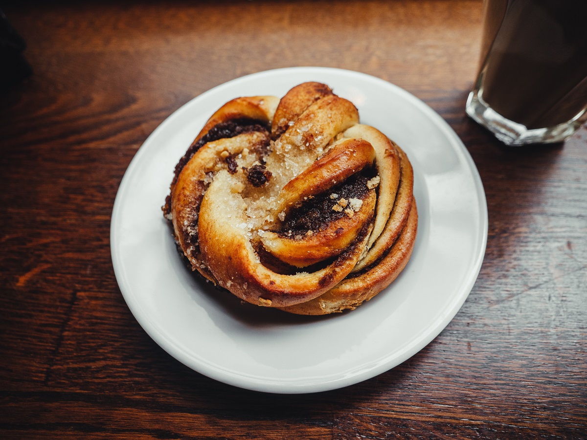 A cardamom bun on a plate with coffee