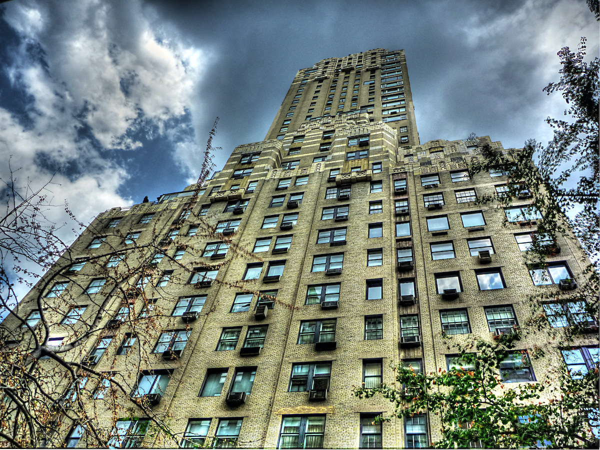 Upward view of multi-story luxury hotel in NYC with beige stone façade.