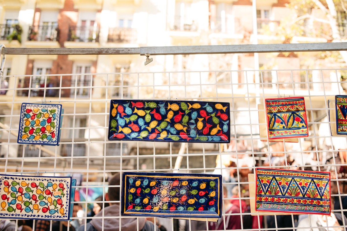 Brightly colored handpainted ceramic trays on display at a flea market.