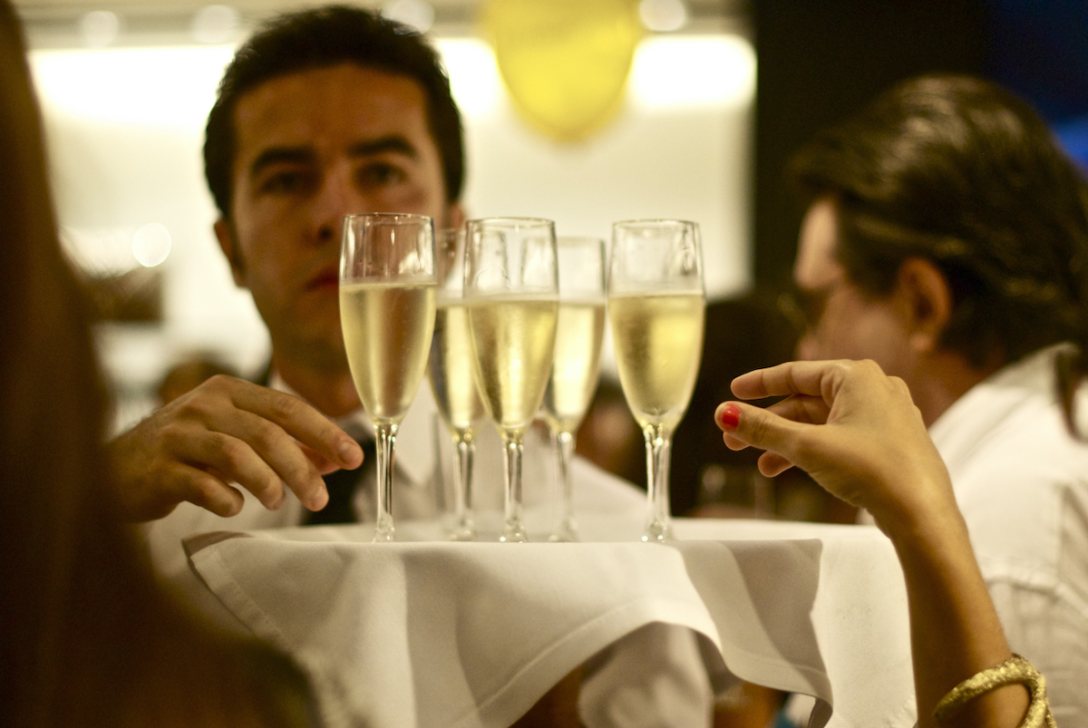 Close up of a waiter holding a tray with several flutes of champagne.