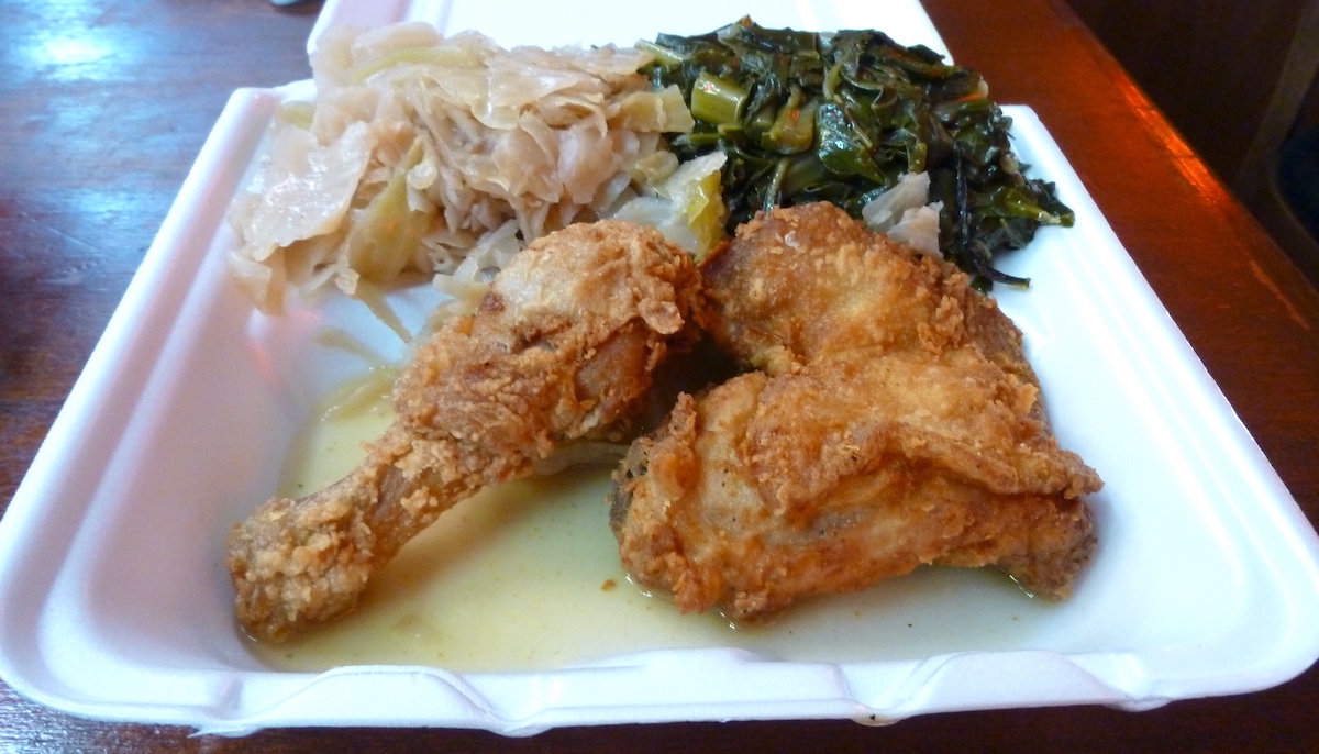 Fried chicken and collard greens served in a styrofoam box